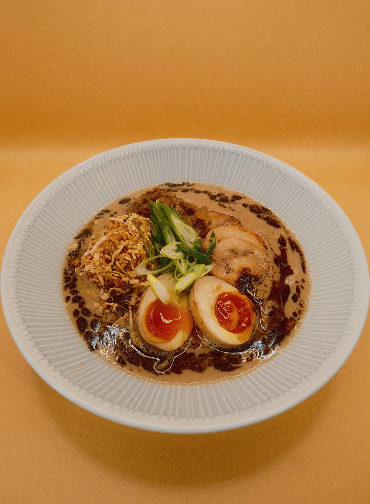 A bowl of Creamy Chicken & Mushroom Ramen on a warm orange background