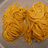 Two nests of golden Sapporo style noodles on a stone plate, one portion each