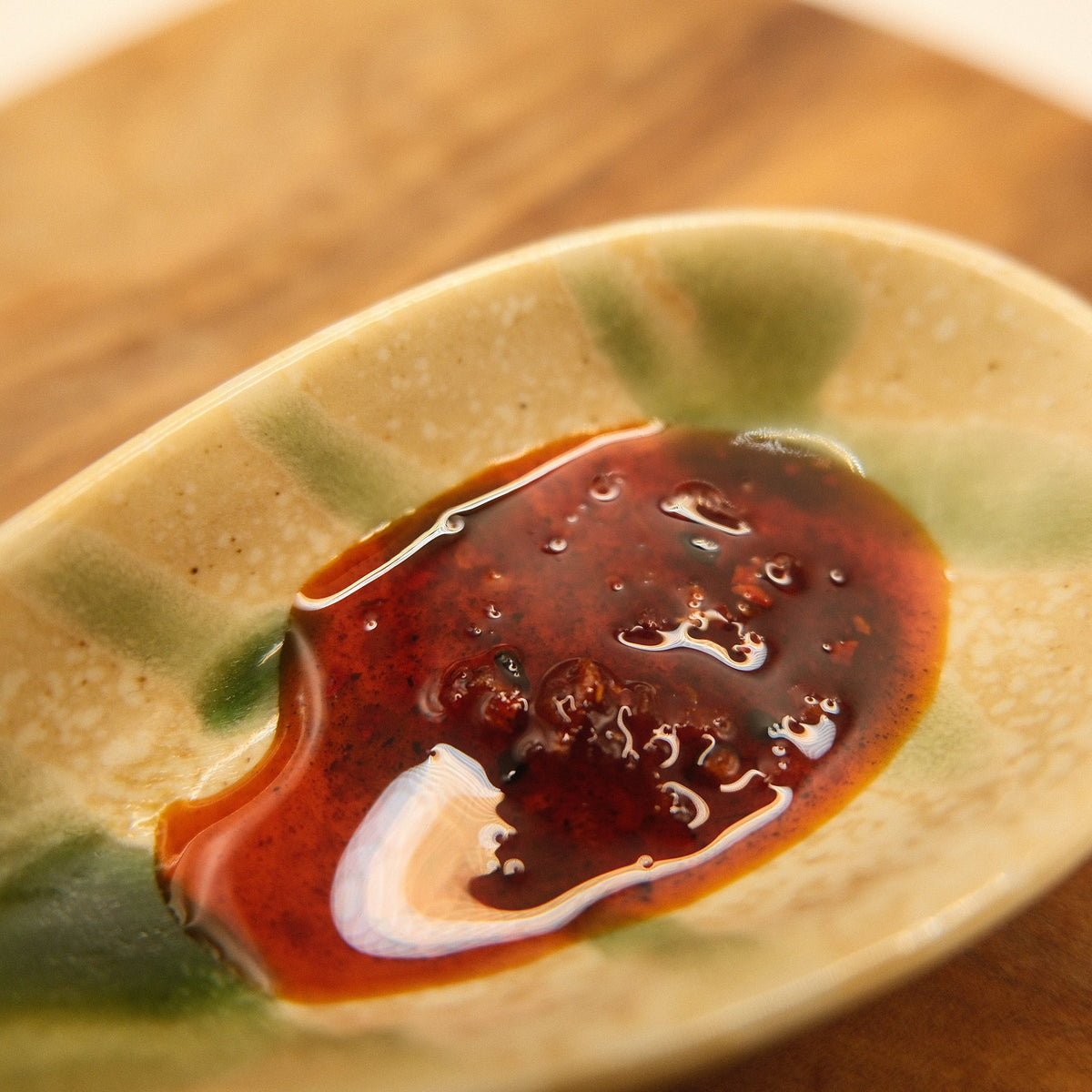 House rayu chilli oil on a ceramic spoon, glossy with flecks of chilli