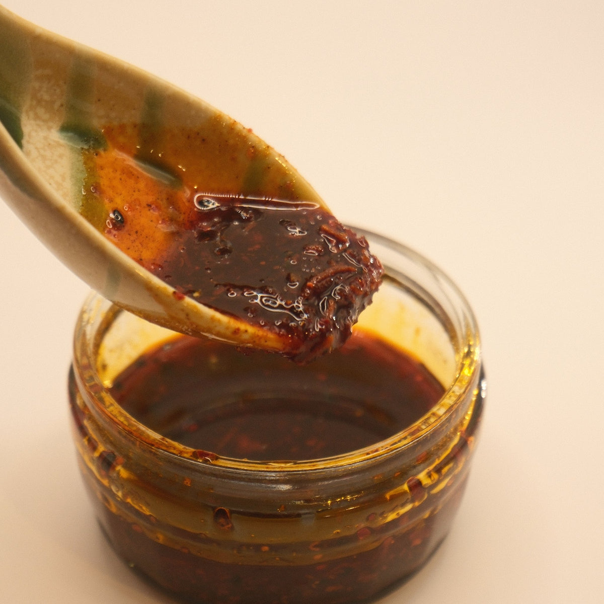 A spoon lifting house rayu chilli oil out of the jar